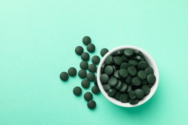 Arka planda spirulina hapları olan bir kase, metin için yer