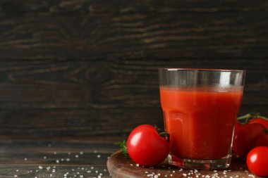 Bir bardak domates suyu, domates ve ahşap zemin üzerinde tuz.