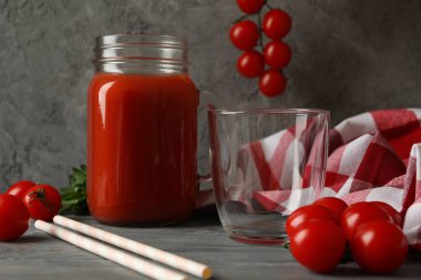 Bir kavanoz domates suyu, domates ve ahşap arka planda mutfak havlusu.