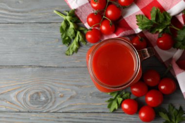 Bir kavanoz domates suyu, domates ve ahşap arka planda mutfak havlusu.