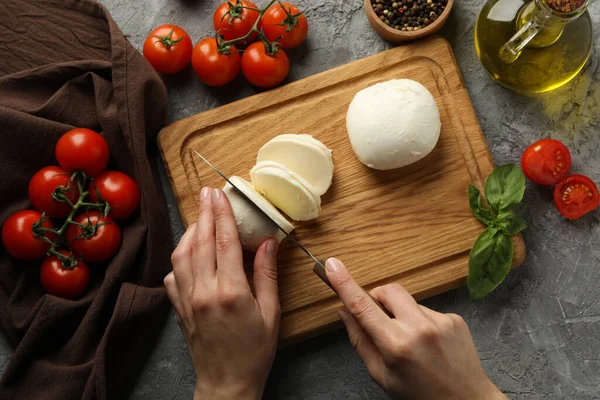 Žena Krájení Mozzarella Dřevěné Desce Šedém Stole Pohled Shora — Stock fotografie