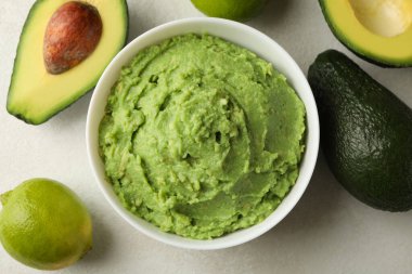 Bir kase guacamole, avokado ve limon beyaz desenli arka plan, üst manzara
