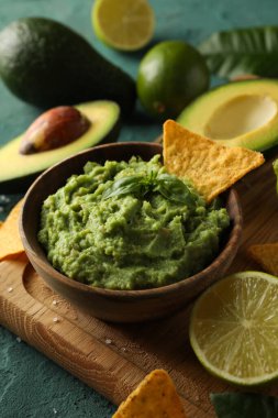Lezzetli yemek kavramı ve yeşil desenli arka planda bir kase guacamole.