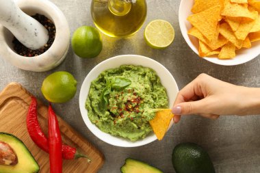 Kadın elini daldırıyor cipsleri dilimliyor guacamole, üst manzara