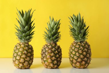 Sarı arka plana karşı üç lezzetli olgun ananas.