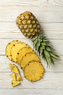 Beyaz ahşap arka planda ananas ve dilimler.