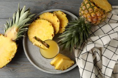 Ananas dilimli tepsi ve ahşap arka planda bir bardak meyve suyu.