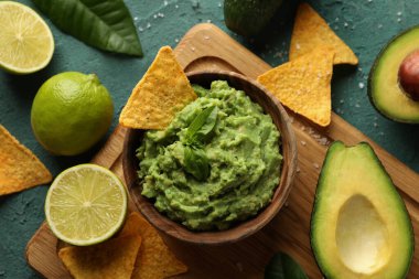 Lezzetli yemek kavramı ve yeşil desenli arka planda bir kase guacamole.