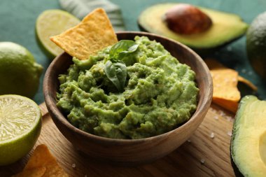 Lezzetli yemek kavramı ve yeşil desenli arka planda bir kase guacamole.
