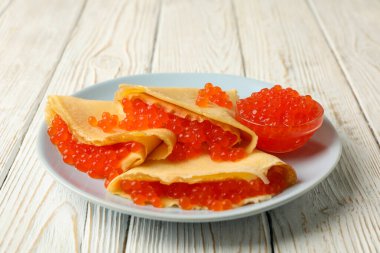 Beyaz ahşap arka planda kırmızı havyarlı krep tabağı.