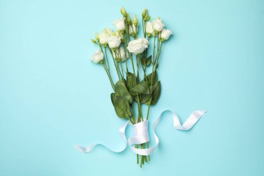 Mavi arka planda kurdeleli bir buket gül.