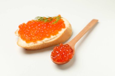 Beyaz arka planda kırmızı havyarlı sandviç ve kaşık.