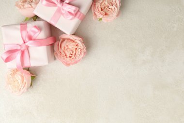 Beyaz desenli arkaplanda hediye kutuları ve güller, metin için boşluk