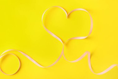 Sarı arka planda kurdeleden yapılmış kalp