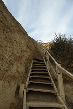 Mavi gökyüzüne karşı ahşap basamaklı kil yamaç