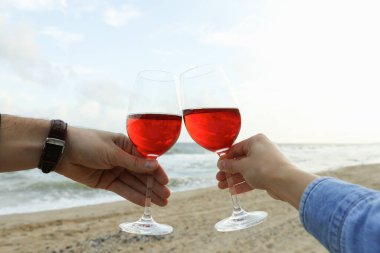 Kadın ve erkek kumsalda şarapla tezahürat yapıyor.