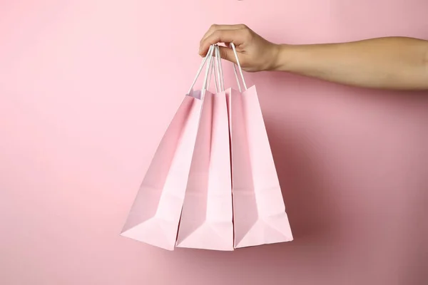女店员手拿着粉色背景的购物袋 — 图库照片