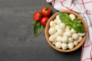 Ahşap arka planda mozzarella ve fesleğen, domates ve havluyla kase, metin için yer