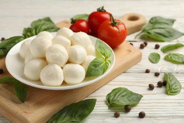 Beyaz ahşap arka planda bir kase mozarella peyniri ile lezzetli yemek kavramı