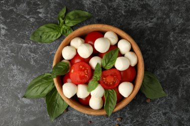 Siyah dumanlı arka planda mozzarella peyniri, domates ve fesleğen.