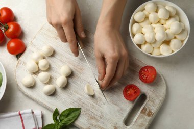 Kesme tahtasında mozzarella dilimleyen kadın, üst manzara.
