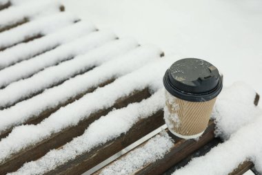 Kışın dışarıda bankta boş kağıt bardak.