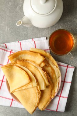 Çay ve gri masanın üzerinde ince krep tabağı.