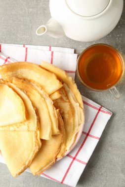 Çay ve gri masanın üzerinde ince krep tabağı.