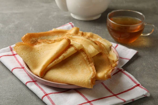 Küchentuch Mit Teller Mit Dünnen Pfannkuchen Und Tee Auf Grauem — Stockfoto
