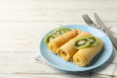 Kahvaltı kavramı, bir tabak krep ve ahşap masa üzerinde kivi dilimleri.