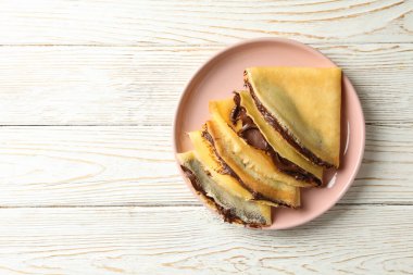 Beyaz ahşap arka planda çikolata ezmeli krep tabağı