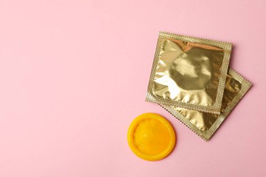 Sarı prezervatif ve pembe arka planda boş prezervatif.