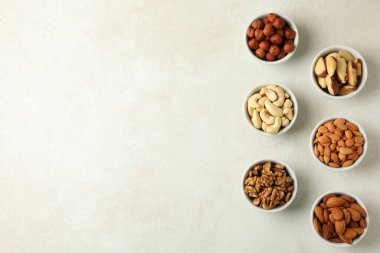 Beyaz desenli arka planda farklı fındıklı kaseler, metin için boşluk