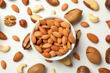 Kayısı tohumlu kase ve beyaz arka planda farklı fındıklar.