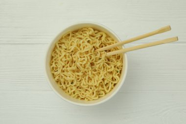 Beyaz ahşap arka planda erişte ve çubuklu kağıt kâse.