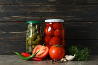 Ahşap arka planda salatalık ve domatesli kavanozlar.