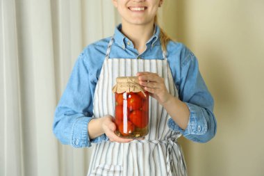 Önlüklü kadın, turşulu domates kavanozu.