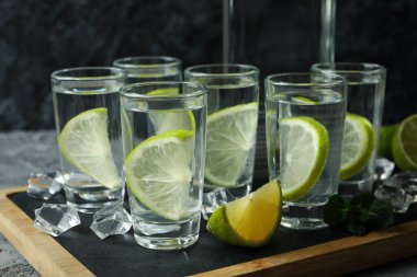 Şişeli tahta ve gri masada limonlu votka.