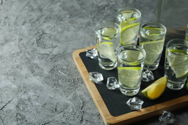 Şişeli tahta ve gri arka planda limonlu votka.