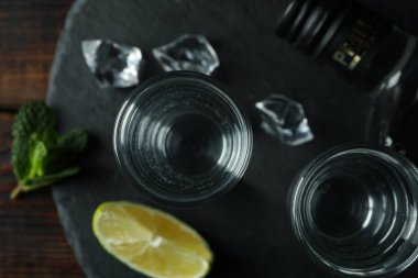 Çekim tepsisi ve tahta arka planda bir şişe votka.