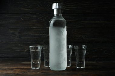 Boş votka şişesi ve tahta arka planda shot.