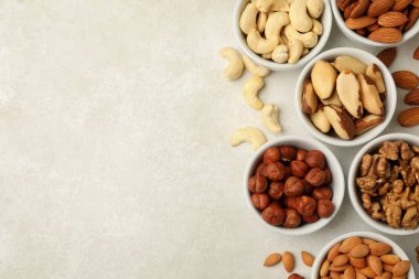 Beyaz desenli arka planda farklı fındıklı kaseler, üst görünüm