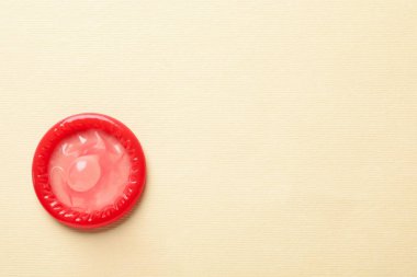Bej arka planda tek kırmızı prezervatif, metin için boşluk