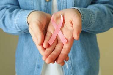 Kadının elinde pembe farkındalık kurdelesi var.