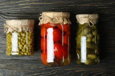 Ahşap zemin üzerinde salatalık ve bezelye turşusu olan kavanozlar.
