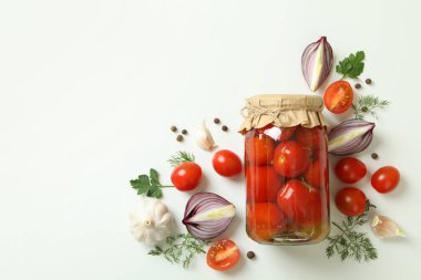 Kavanoz dolusu salamura domates ve malzemeler beyaz arka planda.