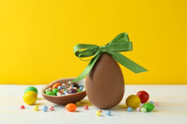 Beyaz ahşap masa üzerinde paskalya çikolatası ve şeker.
