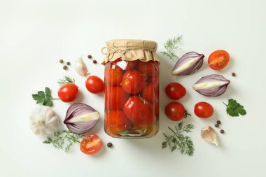 Kavanoz dolusu salamura domates ve malzemeler beyaz arka planda.