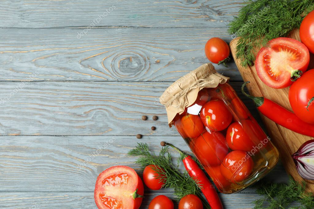 Tarro de tomates en escabeche e ingredientes en mesa de madera 2023
