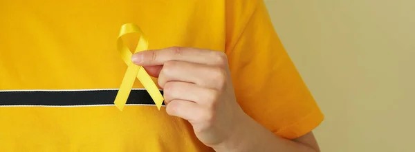Woman in yellow t-shirt hold child cancer awareness ribbon